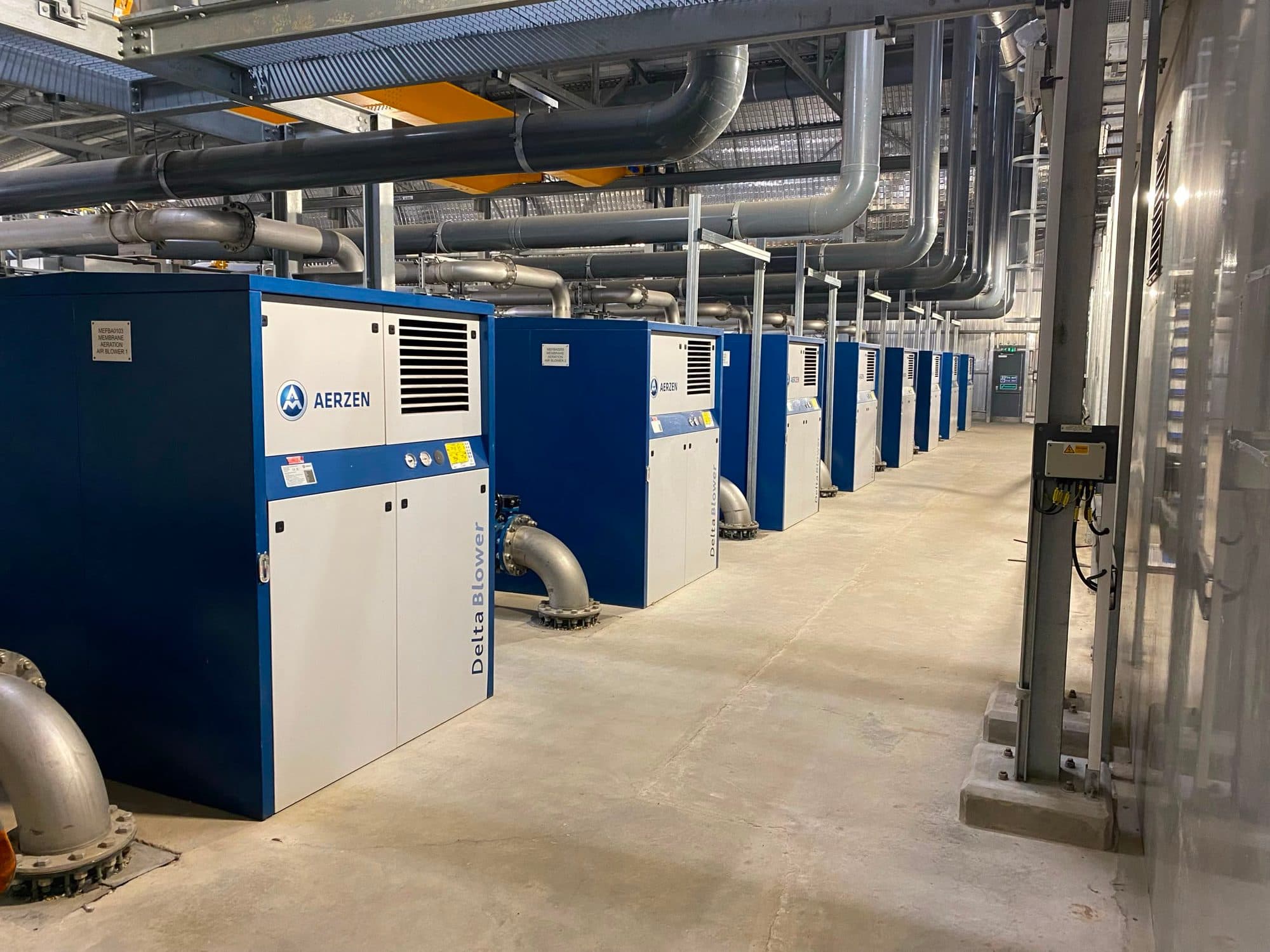 Line of Aerzen Delta blower packages with stainless discharge pipework in an aeration hall