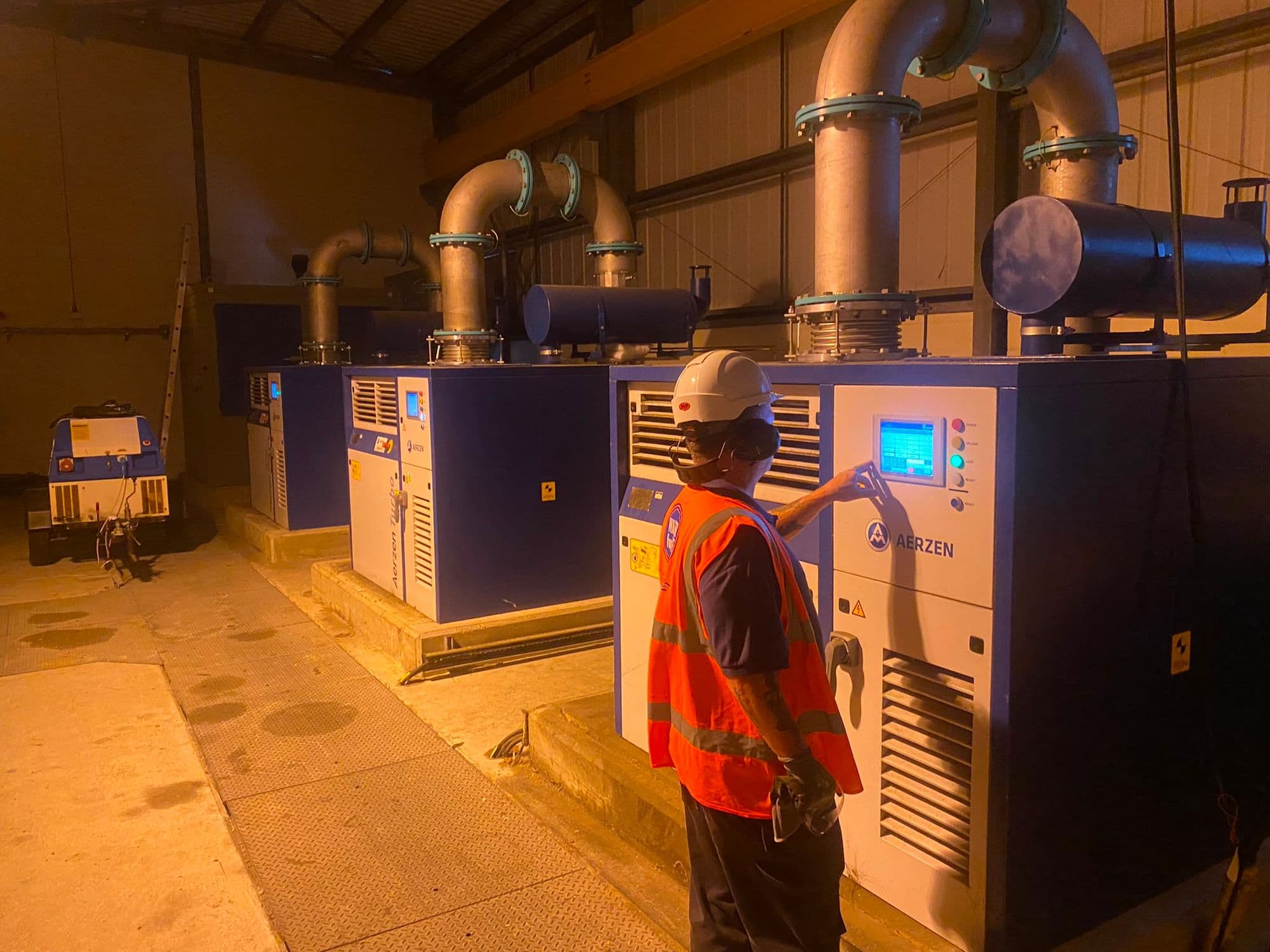 Engineer in hi-vis operating the touchscreen HMI on an Aerzen turbo blower