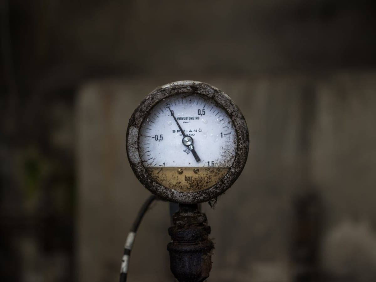 Weathered compound pressure and vacuum gauge reading in bar, mounted on a pipe stub