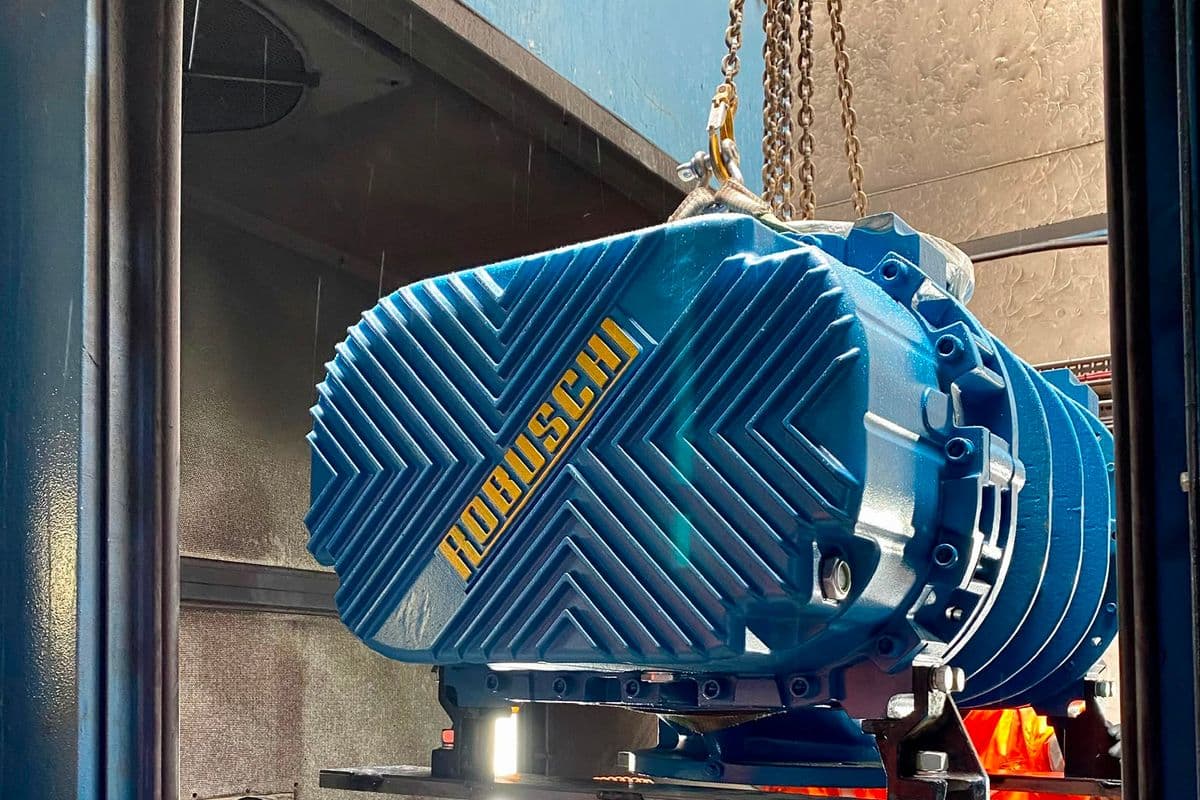 New blue Robuschi lobe blower lifted on crane chains during installation