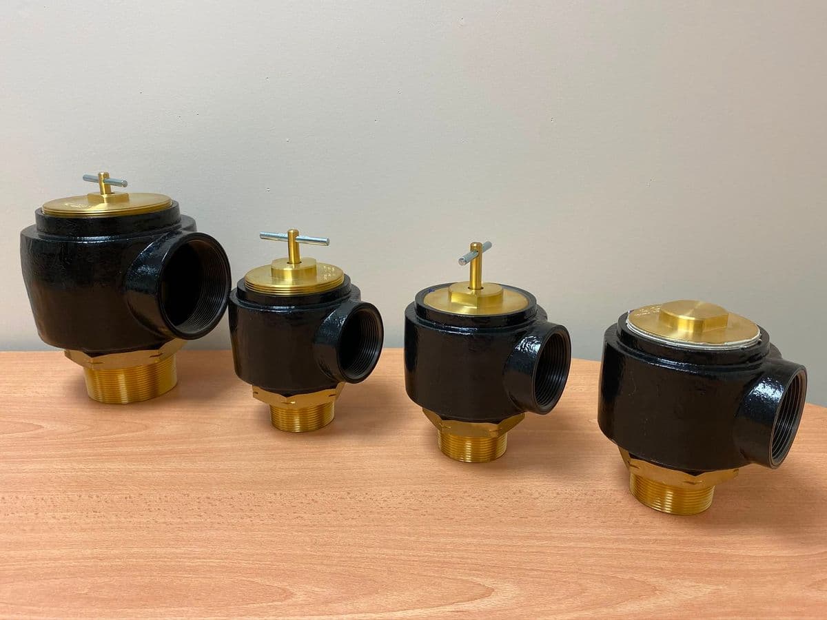 Four pressure relief valves lined up by size on a desk
