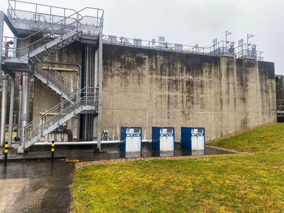 Three Aerzen blower packages beside a concrete aeration tank wall in the rain