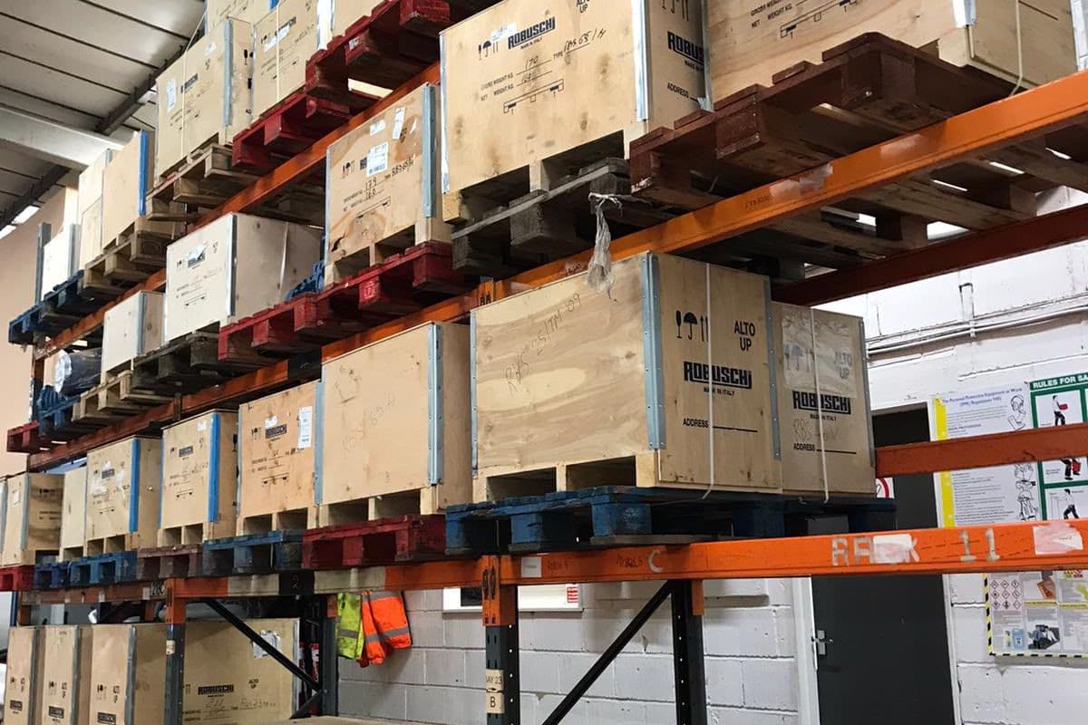 Robuschi spare-part crates stacked on orange pallet racking in the stores