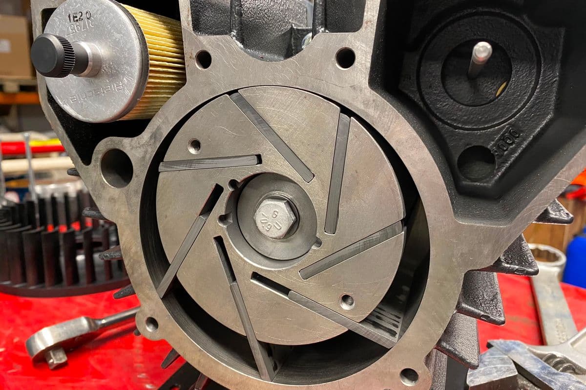 Rotary vane compressor opened on a red workshop bench with its vane rotor exposed